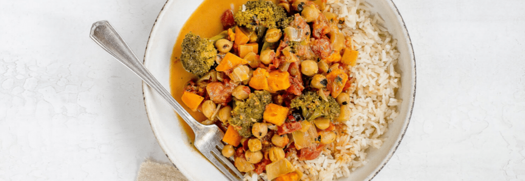 A white plate of chickpea coconut curry with rice