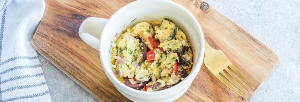 A white mug of Greek flavored scrambled egg omelette